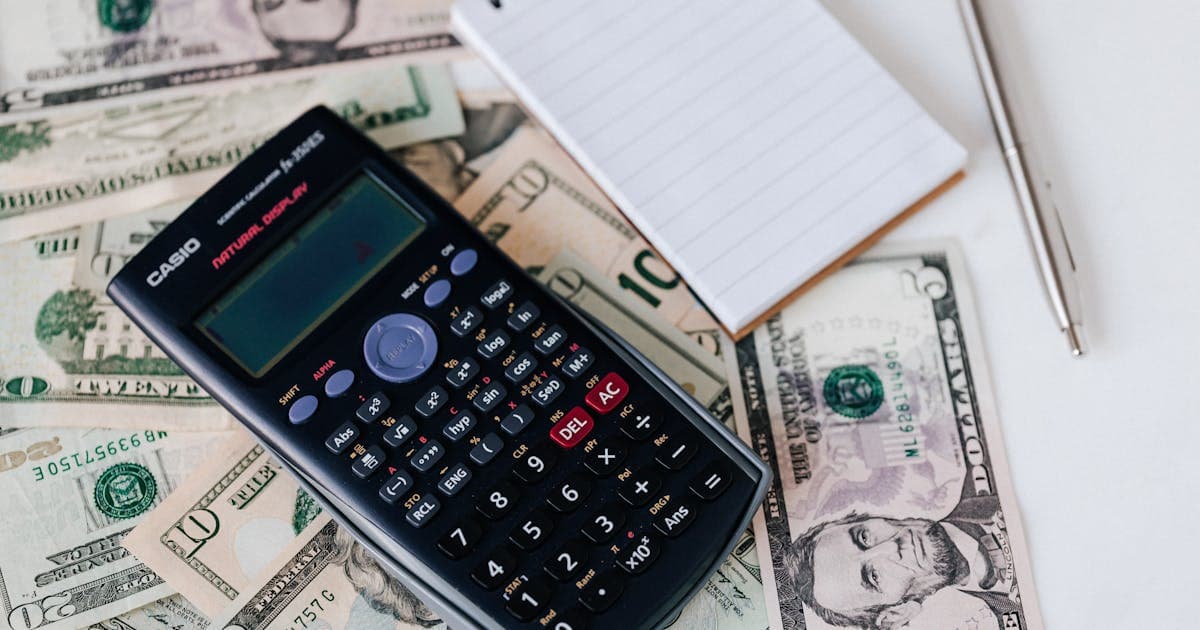 Calculator, money, and notebook on a desk representing budgeting