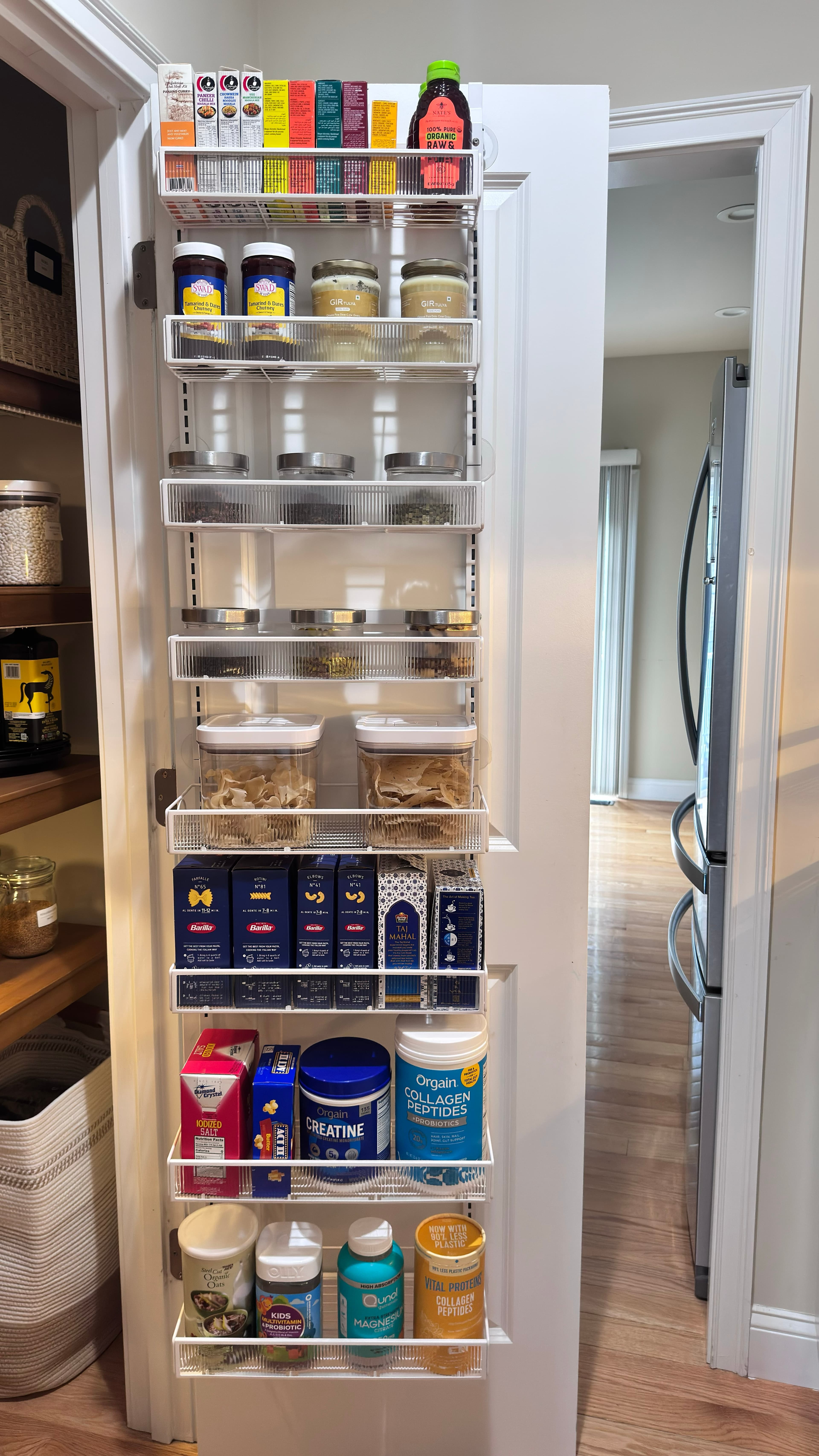 Over-the-door pantry organizer fully stocked with boxed pasta, spices, and supplements